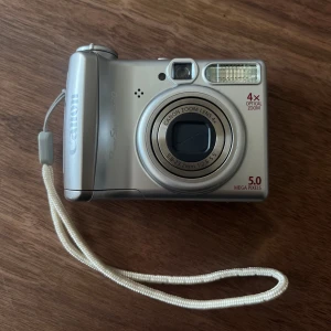 Canon Powershot A530 - En fullt fungerande Canon Powershot A530 digitalkamera. Den är i mycket bra skick! Drivs på AA-batterier så väldigt lätt att ladda.  Finns minneskort (2gb) och sladd så man kan föra över bilderna direkt till telefonen (Lightning). 📸