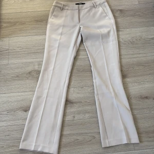 Beiga kostymbyxor från BikBok, strl 36 - Snygga beiga kostymbyxor från BikBok. Byxorna har dock en liten svart fläck längst när på ena benet men inget man tänker på. Köparen står för frakten