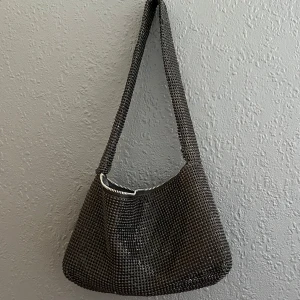 Svart rhinestone axelväska  - Cool svart axelväska från Bik Bok med rhinestones över hela väskan. Väskan har en mjuk, rundad form och stängs med dragkedja. Perfekt för att lyfta din outfit med lite extra bling. Lite trasig på sina ställen (se bild) men inget som stör funktioner och syns ej på håll!