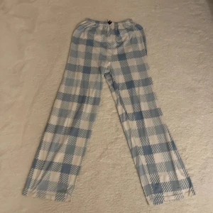 Blåvita rutiga mjukisbyxor - Säljer ett par mjukisbyxor med blåvitt rutigt mönster och resår i midjan. Byxorna har raka ben och är gjorda i mjukt bomullstyg, perfekta för chill dagar hemma. Snyggt och avslappnat vibe!