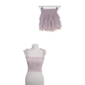 Blommig volangkjol och topp från Defox S/M - Supersöt kort volangkjol och topp från Defox i blommigt mönster med lila, orange och gröna toner. Kjolen har flera lager volanger och resår i midjan för en bekväm passform. Perfekt för dig som gillar en romantisk och somrig stil.