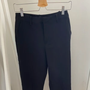 Svarta kostymbyxor från BikBok - Klassiska svarta kostymbyxor från BikBok i stilren design. Byxorna har raka ben, hällor för bälte och diskreta fickor framtill. Nypris 500kr