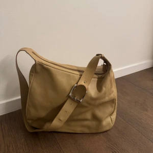 Vintage handväska - Säljer min super fina vintage handväska i mjukt skinn med justerbart axelband och silvrigt spänne. Man kan justera väskan och ha den över axeln, dator hörlurar och böcker får plats i väskan. Perfekt till vardag!! Perfekt för dig som vill ha en enkel men snygg väska med mycket plats.