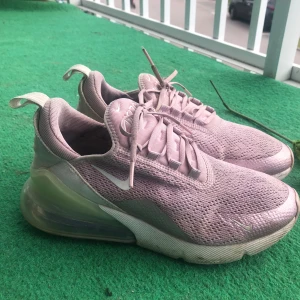 Nike Air Max 270 i ljuslila, strl 37.5 - Nike Air Max 270 sneakers i en snygg ljuslila färg med mesh-ovandel och stor synlig Air Max-bubbla i hälen. Skorna har snörning och en sportig vibe, perfekt för dig som gillar streetstyle. Swoosh-logga på sidan och detaljer i vitt.