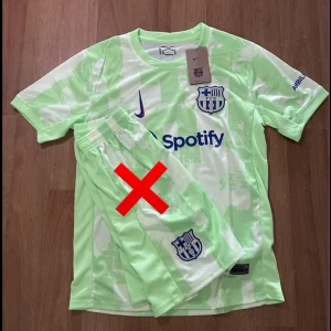 FC Barcelona 24/25 away kit inspirerad fotbollströja - FC Barcelona matchtröja  i ljusgrönt med vita detaljer och tryck. Tröjan har klubbmärke på bröstet, sponsorloggor och korta ärmar. Tillverkad i lätt och ventilerande material, perfekt för fotbollsträning eller match.