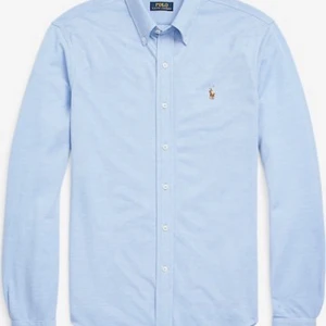 Ljusblå skjorta från Polo Ralph Lauren - Klassisk ljusblå skjorta från Polo Ralph Lauren med broderad logga på bröstet. Skjortan har lång ärm, knappar hela vägen och button-down krage. Perfekt för en clean och stilren look.