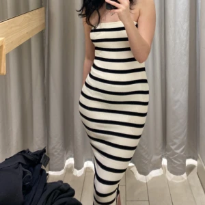 Randig ribbad tube långklänning - Säljer en snygg axelbandslös långklänning med svartvita horisontella ränder. Klänningen är ribbad och har en tight passform som framhäver figuren. Perfekt för dig som gillar en stilren och trendig look. 