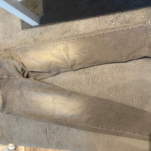 Grå jeans från Replay - Säljer ett par grå jeans från Replay med klassisk femficksdesign. Jeansen har raka ben och är tillverkade i ett mjukt bomullsmaterial. Snyggt slitna detaljer och diskret tvättad look ger en avslappnad vibe.