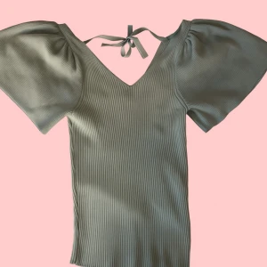 Ljusgrön ribbad topp med puffärmar och knyt i ryggen - Superfin ljusgrön topp med ribbad struktur och puffiga korta ärmar. V-ringad både fram och bak med en söt knytning i ryggen. Storlek S, från ONLY