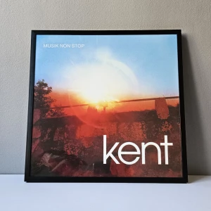 Kent - Albumaffisch, 31.5x31.5cm - Kent - Musik non stop albumaffisch, 31.5x31.5cm  Passar bra i IKEAs tavelram Lomviken!  Skickas i papprulle - Ramen ingår inte!