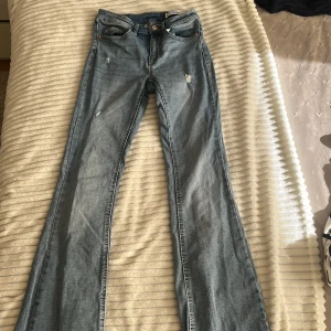 Bootcut jeans från Vero Moda XS - Mellanblå bootcutjeans med låg midja och slitningar, de är i bra skick och har inga defekter. De är köpa från Vero Moda för några månader sen 