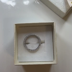 En silverringar med stenar - Säljer en rostfri stilren silverring. Det är en klassisk slät ring i silver med gnistrande stenar runt hela bandet inuti. M/S på storleken.