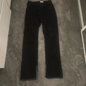 Svarta jeans från Hanna Schönberg x NA-KD - Svarta jeans med raka ben och råa, fransiga benslut från Hanna Schönberg x NA-KD. Klassisk femficksmodell med hög midja och knappgylf. Snygga till sneakers eller boots och passar perfekt till en avslappnad streetstyle.