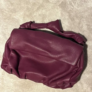 Väska med knutdetalj - Lila/vinröd väska från Gina Tricot med knytdetaljer. Mellanstor storlek som får plats med mycket 