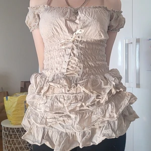 Beige offshoulder korsettopp med volanger - Supersöt beige korsettopp med offshoulder och volanger. Toppen har snörning framtill och fina detaljer. Pris går att diskuteras💞