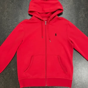Röd hoodie från Polo Ralph Lauren - En använd fräsh tröja i storlek S. Den har en skada på vänstra snöret. Annars är den i ett bra skick 