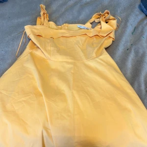 Gul kort klänning från LCW Casual - Superfin gul kort klänning från LCW Casual med volangdetalj upptill och knytbara axelband. Perfekt för varma dagar och har en lätt och luftig känsla. Klänningen har en feminin och söt stil som passar perfekt till sommaren.