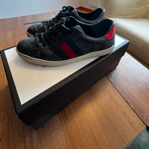 Gucci ace  - Snygga svarta sneakers från Gucci med några skavanker men inget man tänker på under daglig användning. Kan diskutera pris vid snabbt köp!! Ps passar 41 42