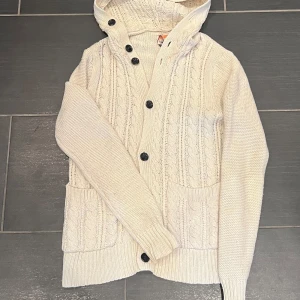 Stickad vit cardigan - Riktigt snygg cardigan med luva. Cardiganen är väldigt detaljerad och bra kvalité. Hör av dig vid minsta fråga!