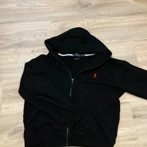 Polo Ralph Lauren hoodie - Säljer en svart hoodie från Ralph Lauren med dragkedja. Har dragit ut snöret för att de blev inte så snyggt🙂Strl M men passar även S. Hör av er om ni funderar nått😊