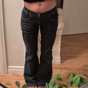 Low jeans med bootcut - Snygga jeans med unika röda sömmar och detaljer. Byxorna har en låg midja och en bootcut-stil. På sista bilden kan man se en liten defekt, sömnen är löst men det är en enkel fix. Jag är 155cm 