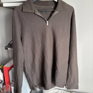 Grön tröja med dragkedja från JacknJones - Säljer en stilren mörkgrön tröja från Jacknjones med dragkedja vid halsen. Tröjan har långa ärmar och en klassisk krage. Perfekt för en avslappnad look.