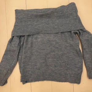 Grå offshoulder tröja från Pull&Bear - Säljer en slutsåld ljusblå offshoulder tröja från Pull&Bear. Tröjan är stickad med ribbade detaljer och har långa ärmar. Använt ett par gånger men har inte några defekter eller fläckar.