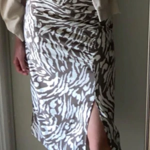 Brun och vit mönstrad kjol från Vila - Snygg kjol från Vila med zebramönster som är i storlek 34. Kjolen har en slits på sidan och är i fint skick.🤍Säljs för 200kr men priset kan diskuteras.