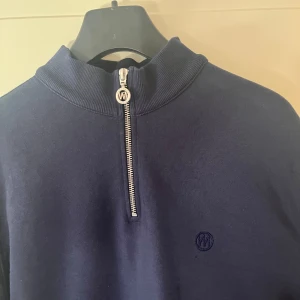 Quarter zip från westmark london - Säljer en stilren mörkblå tröja från Westmark London med en praktisk dragkedja framtill. Tröjan har en diskret logga på bröstet och en ribbad krage. Perfekt för en avslappnad men snygg look.