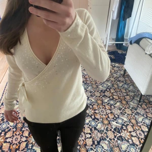 Vit omlottopp med paljetter - Säljer en elegant vit omlottopp med paljetter.