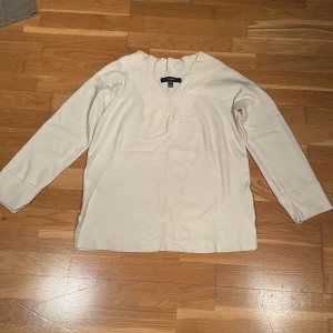 Beige tröja från Vero Moda - Säljer en stilren beige tröja från Vero Moda. Tröjan har en v-ringad design med ribbade detaljer vid halsen och ärmsluten. Perfekt för en avslappnad och elegant look.