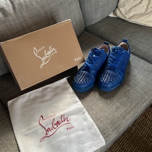 Blå sneakers med nitar från Christian Louboutin - Snygga blå sneakers från Christian Louboutin med coola nitar på tån. Skorna har snörning och en stilren design som verkligen sticker ut. Perfekta för dig som vill ha något unikt och trendigt i garderoben. Använda ett par fåtal gånger därav priset. Stl 44 med passar också till er som har 45. Kan gå ner lite i pris vid en eventuell snabb affär.