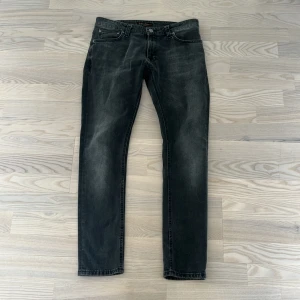 Nudie Jeans  - Snygga svarta jeans från Nudie Jeans med en klassisk femficksdesign. De har en diskret tvättad look och märkets signaturbroderi på bakfickan. Perfekta för en stilren vardagslook. Mer info eller bilder hör dig!