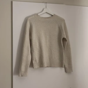 Beige stickad tröja från Vero Moda - Säljer en mysig beige stickad tröja från Vero Moda. Tröjan har en klassisk design med långa ärmar och ribbade muddar vid ärmslut och nederkant. Perfekt för kyliga dagar!