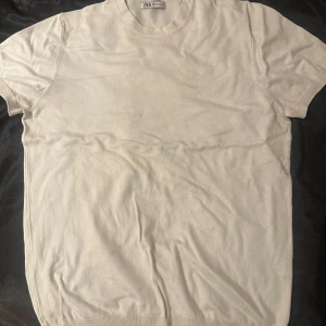 Vit t-shirt från Zara - Säljer en klassisk vit t-shirt från Zara i storlek M. T-shirten är kortärmad och tillverkad i ett mjukt material som ger en skön känsla. Perfekt basplagg för alla tillfällen.
