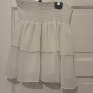 Vit kjol från Chelsea - Säljer en söt vit kjol från Chelsea med smockdetaljer i midjan och flera lager för en voluminös look. Perfekt för varma dagar och kan enkelt matchas med olika toppar. 🩶