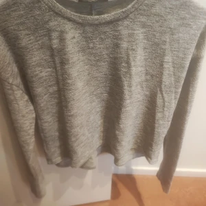 Grå långärmad tröja från FB Sister - Säljer en stilren grå långärmad tröja från FB Sister. Perfekt för en avslappnad look. Tröjan har en rund halsringning och är gjord i ett mjukt material som känns skönt mot huden.