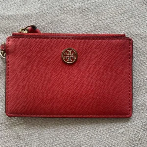 Röd plånbok från Tory Burch - Röd korthållare från Tory Burch med en nyckelring så att man kan sätta fast den i väskan för extra säkerhet. Kostar 1200 kr i nypris.  