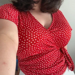 Röd prickig omlottopp  - Säljer en söt och röd omlottopp med vita prickar då den inte passar mig. Toppen har korta ärmar och en knytning i sidan som ger en fin passform. Köpt på Vinted men är i fint skick.  🍒 hund finns i hemmet