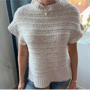 Beige stickad tröja från Lindex  - Säljer en mysig beige stickad tröja med korta ärmar och ribbad struktur. Perfekt för lager-på-lager under kyligare dagar. Tröjan har en hög krage som ger extra värme och stil. Lånad bild🥰