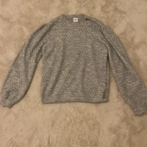 Grå stickad tröja från Stories - Säljer en mysig grå stickad tröja från Stories i storlek XS. Tröjan har ett diskret mönster och långa ärmar, perfekt för kyligare dagar. Den är både stilren och bekväm, ett måste i garderoben! 💫