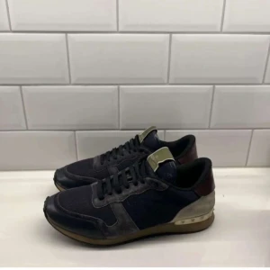Valentino Rockrunner - Säljer dessa feta Valentino Rockrunner Sneakers i mörkblå färg. Skorna är väldigt bekväma och är i ett använt skick men ända bra skick.  Skorna är storlek 43,5 men passar allt upp till 45. Priset är diskutabelt vid snabb affär. Hör av er vid mer frågor samt funderingar!