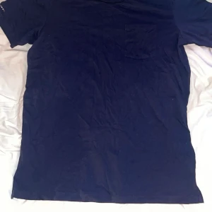 Mörkblå t-shirt från Race Marine - Säljer en stilren mörkblå t-shirt från Race Marine. Den har en klassisk passform med korta ärmar och en liten bröstficka. Perfekt för en avslappnad look.