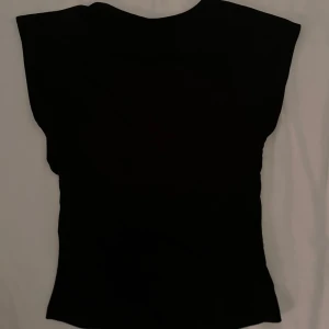 Svart open back topp - Snygg svart topp med öppen rygg. Perfekt för en stilren look. Passar bra till både jeans och kjol.