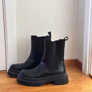Svarta chelsea boots - Snygga svarta chelsea boots med grov sula. Perfekta för både sommar, höst och vinter. De har en klassisk design med elastiska paneler på sidorna för enkel på- och avtagning.