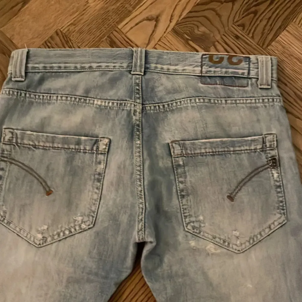 Snygga ljusblå jeans med en cool tvättad look och slitningar från dondup. De har en klassisk femficksdesign och en knappgylf. Perfekta för en avslappnad stil.. Farkut & Housut.