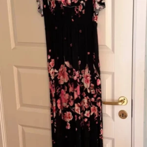 Hollister blå  långklänning med blommönster - Elegant blå  långklänning med vackert rosa blommönster. Klänningen har korta ärmar och en feminin passform som passar perfekt för festliga tillfällen. Den är tillverkad i ett mjukt och följsamt material som ger en bekväm känsla.