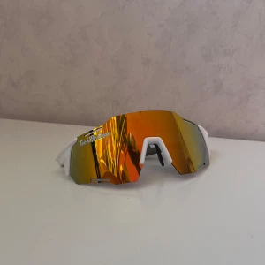 Sportiga solglasögon med spegelglas - Snygga sportiga solglasögon från TechFit Gear med spegelglas i orange och vit båge. Perfekta för utomhusaktiviteter med en modern och cool design.
