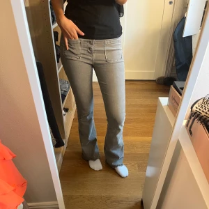Grå bootcut jeans med stora fickor - Snygga grå jeans från Green Coast med bootcut passform och stora, markerade fickor både fram och bak. Jeansen har medelhög midja och flera knappar framtill. Materialet är mjukt och stretchigt jeans-tyg som sitter skönt. Perfekt för dig som gillar en cool och avslappnad stil.