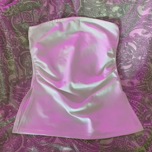 Vit axelbandslös tubtopp - Säljer en stilren vit axelbandslös tubtopp med slits på sidorna, perfekt nu till sommaren!! Storlek S, nypris 150kr. Aldrig använd, endast provad🤍